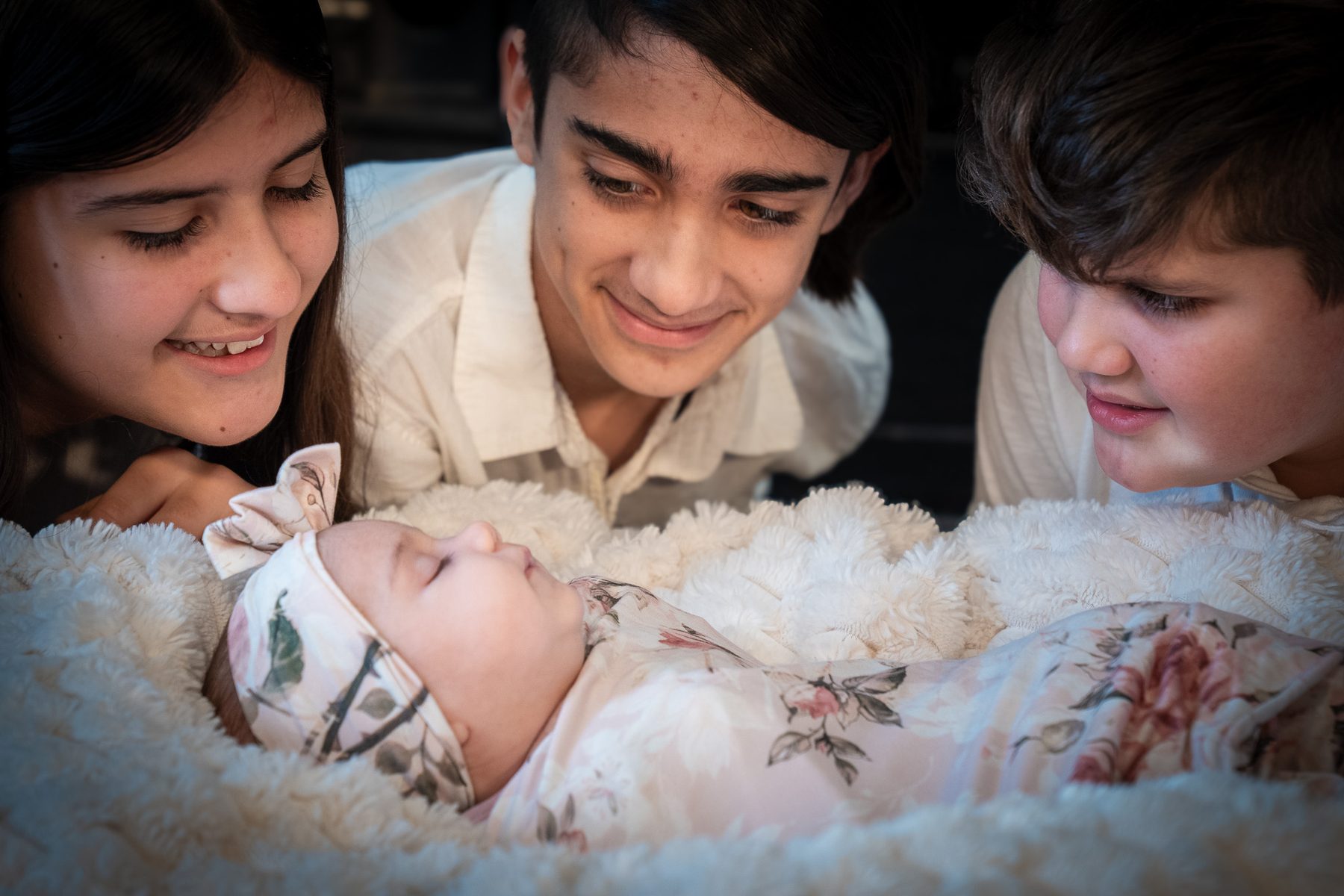 Siblings gathered around a newborn